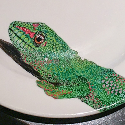 A dinner plate with a painted lizard